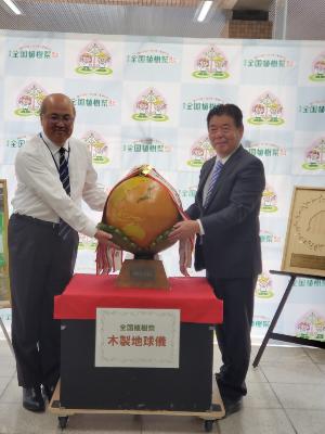 市役所のロビーで、県から地球儀を受け取る萩原市長